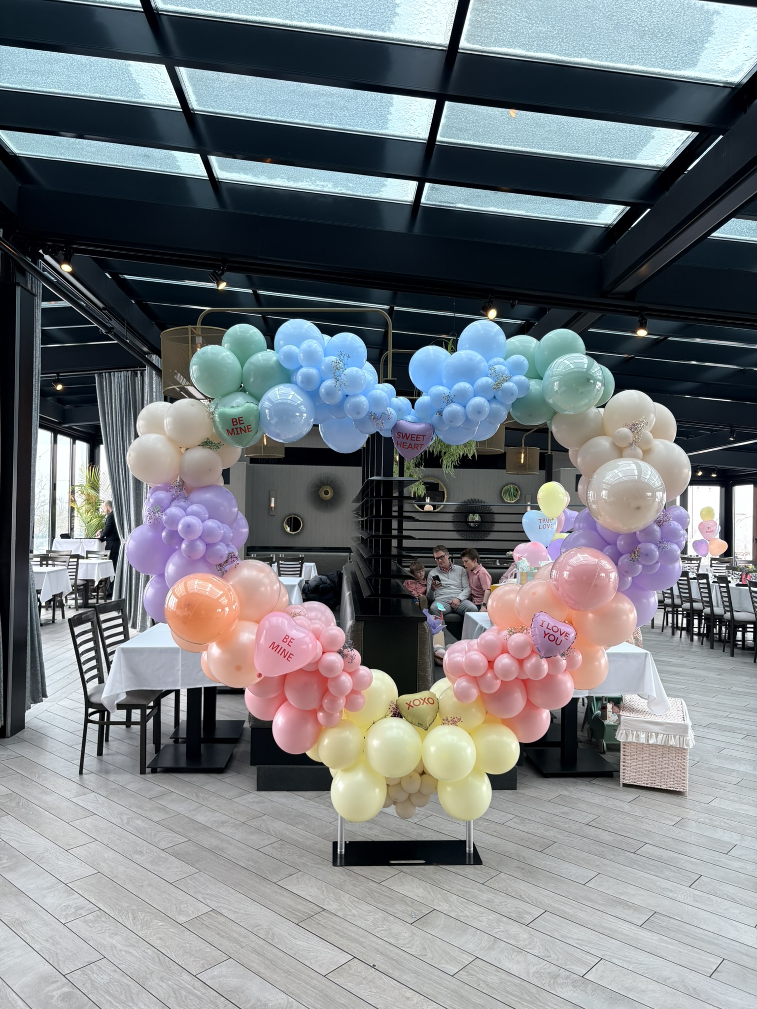 Large circular freestanding balloon installation with pastel conversation hearts for dual-themed Valentine's baby shower Providence RI